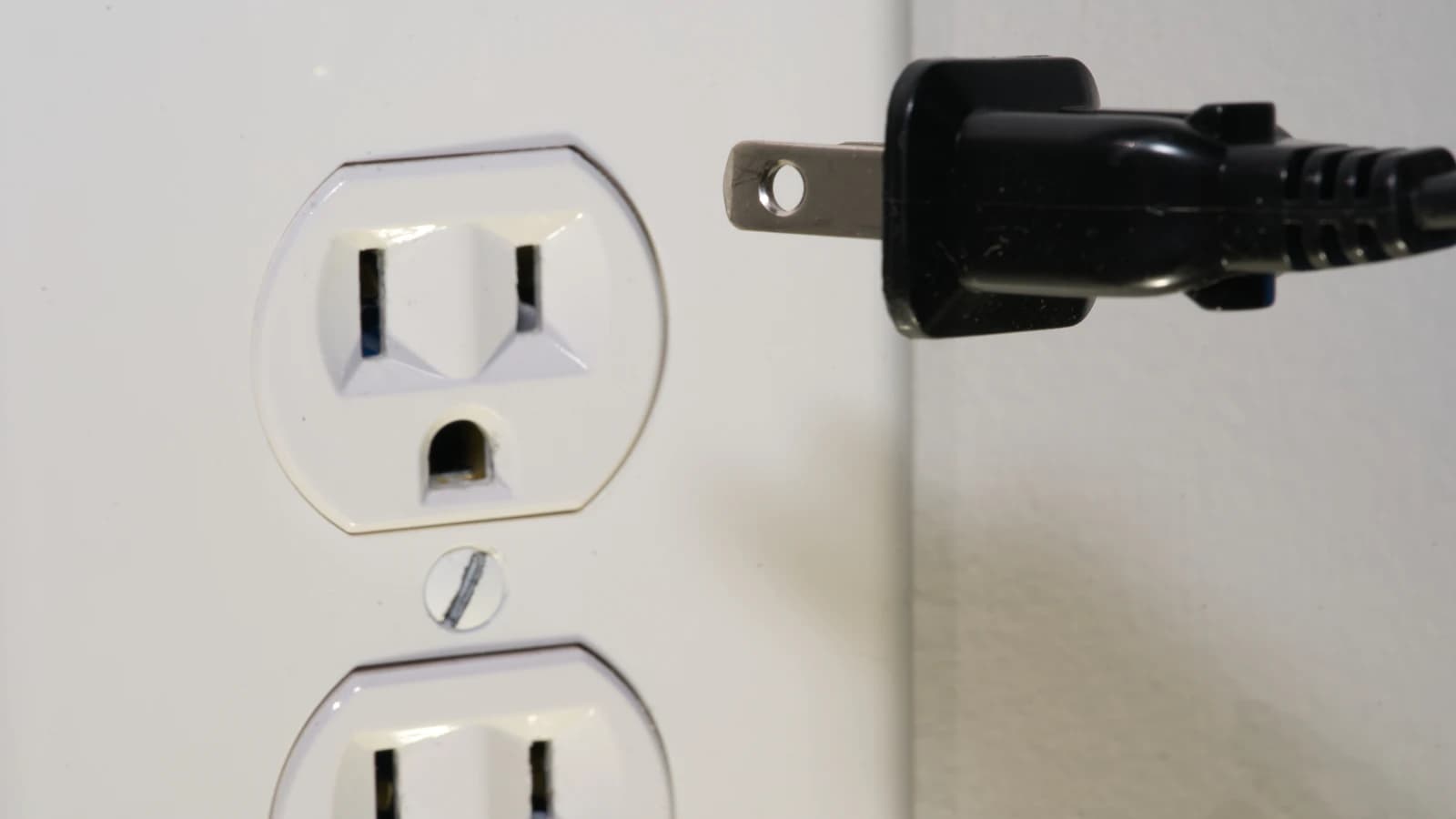 Elektricien plaatst een nieuw stopcontact in een muur