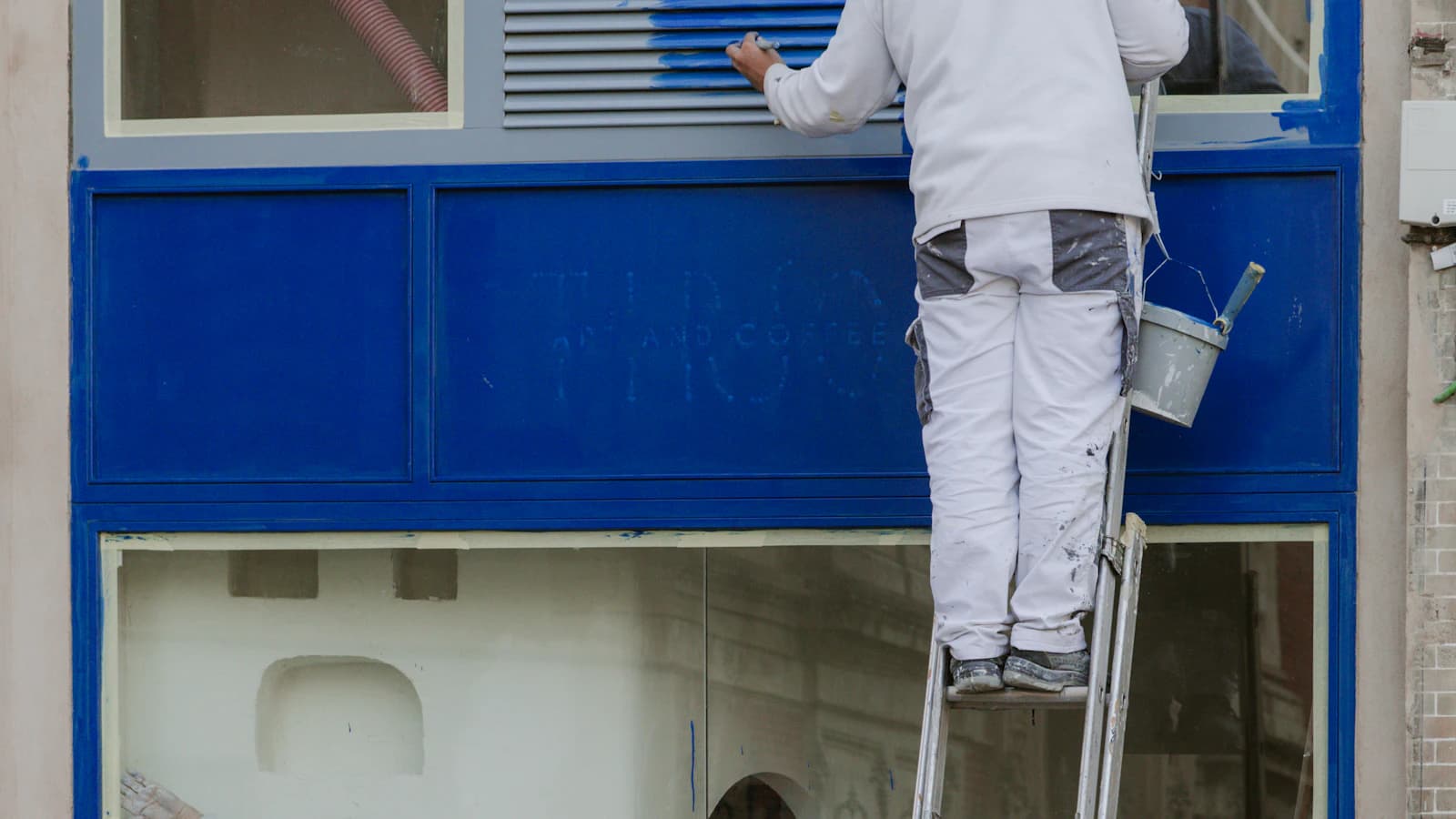 Schilder schuurt en schildert een houten raamkozijn buiten