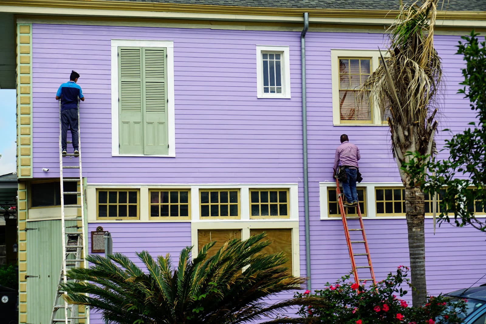 Schilder schildert een woninggevel vanaf een stelling