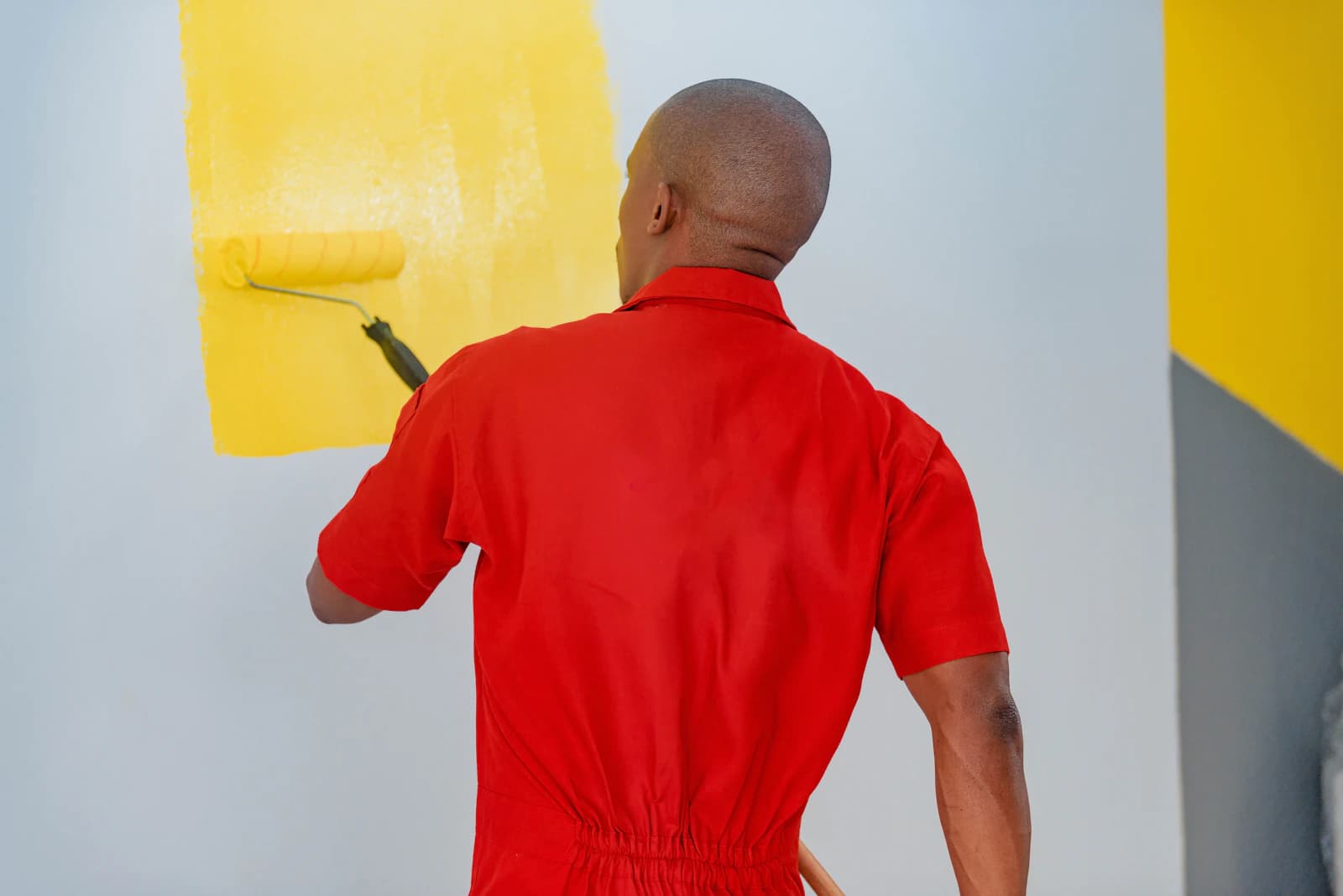 Schilder spuit latex op een muur met een verfspuit