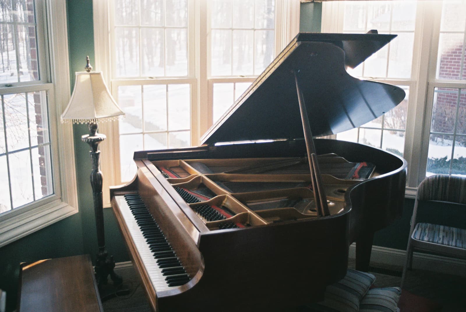 Verhuizers tillen voorzichtig een piano met speciaal materiaal