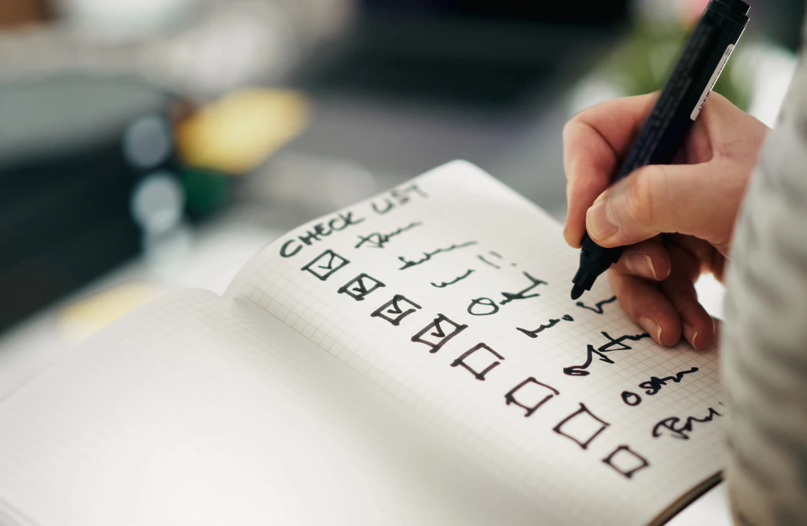 Verhuischecklist afvinken met verhuisdozen op de achtergrond